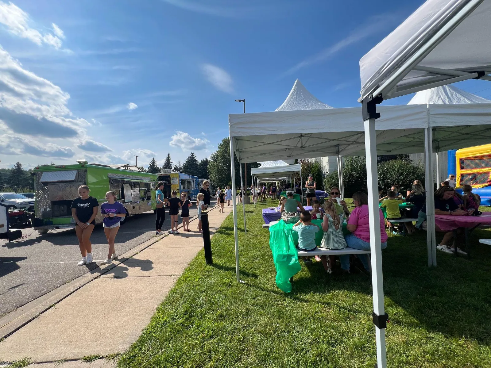 Tents and food trucks along a sidewalk at an outdoor community fair